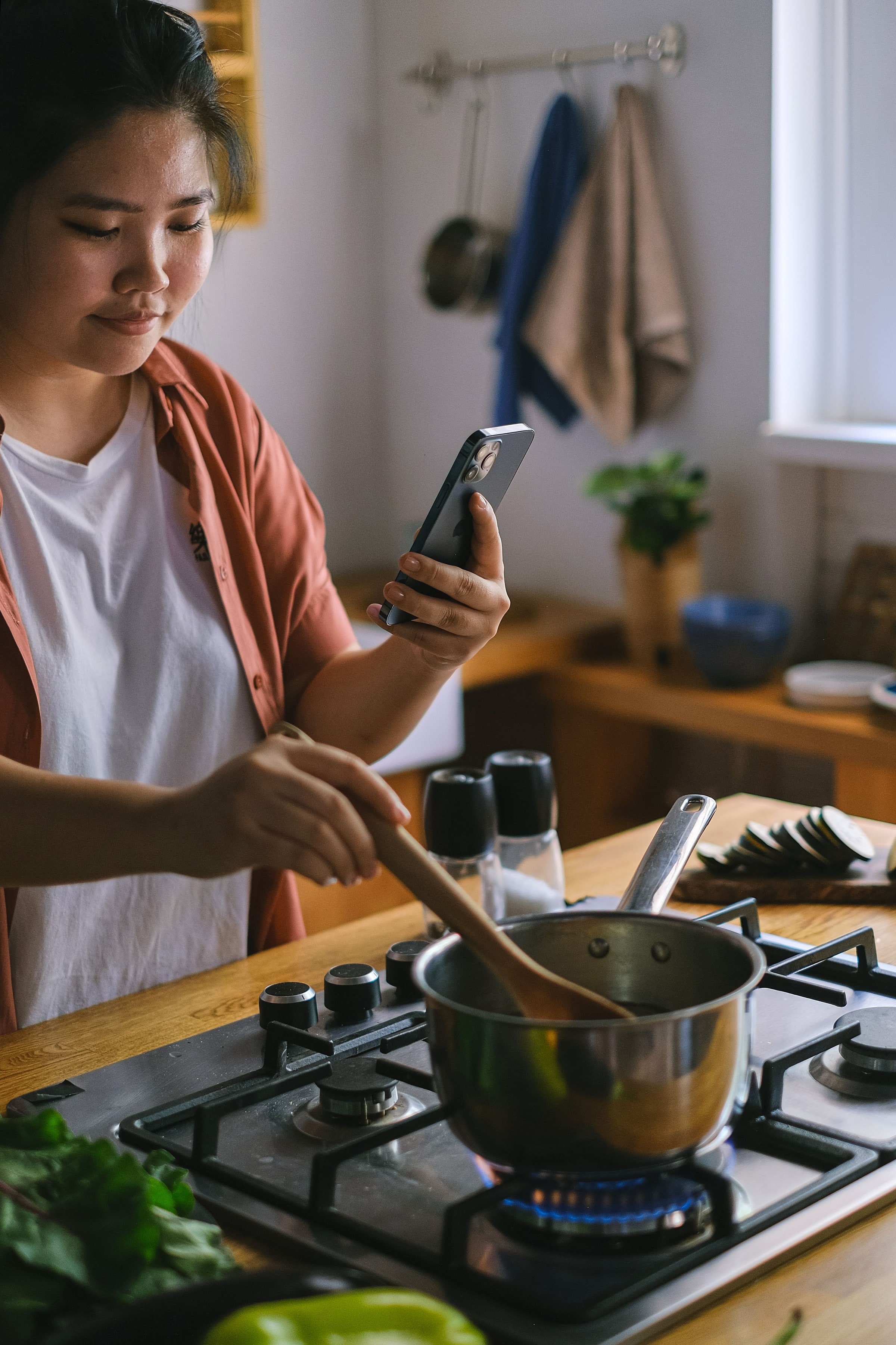 Une femme consulte une recette sur son téléphone tout en cuisinant